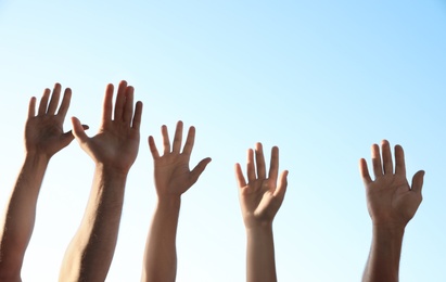 Group of volunteers raising hands outdoors, closeup