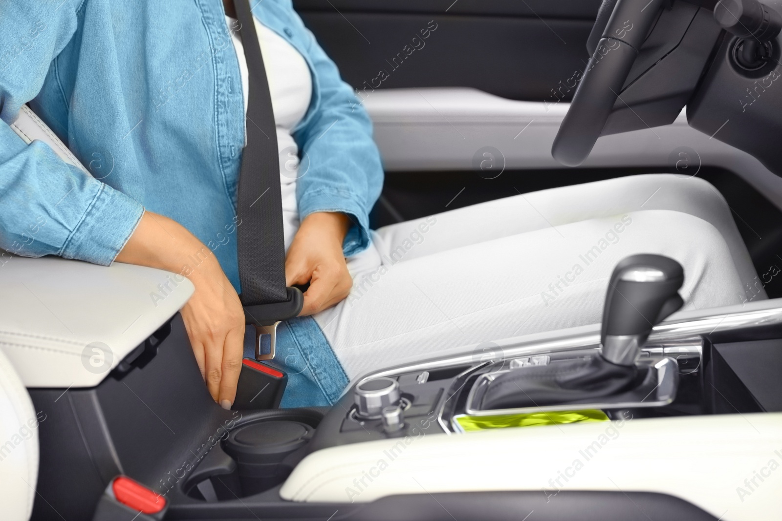 Photo of Female driver fastening safety belt in car, closeup