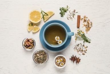 Photo of Flat lay composition of freshly brewed tea with chamomile flowers and dry leaves on white wooden table
