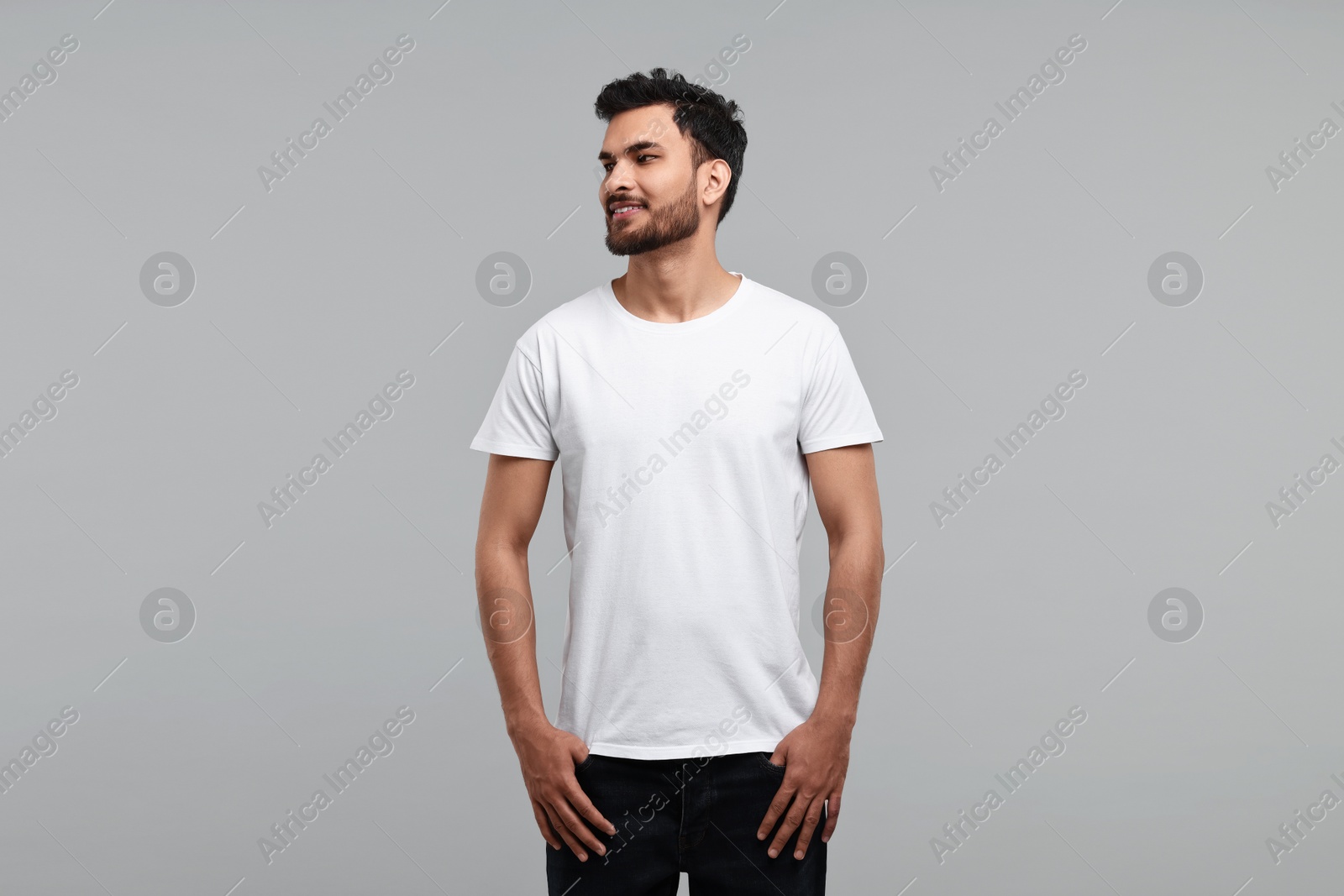 Photo of Smiling man in white t-shirt on grey background