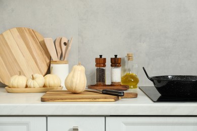 Photo of Wooden cutting boards, other cooking utensils and pumpkins on white countertop in kitchen