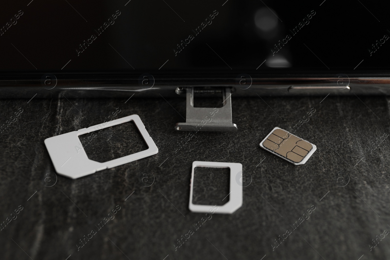Photo of SIM card and mobile phone on grey table, closeup
