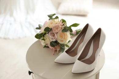 Pair of wedding high heel shoes and beautiful bouquet on white table