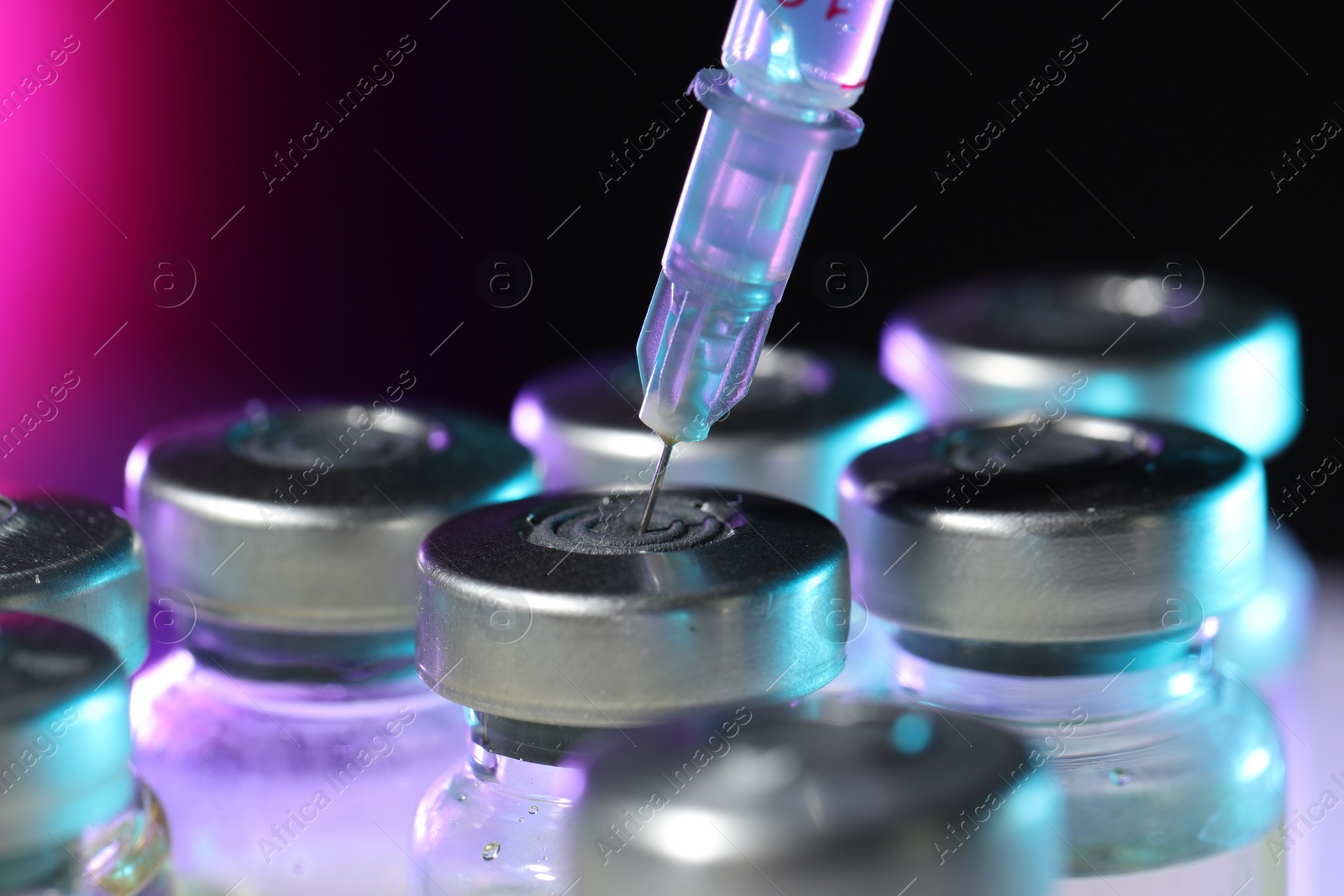 Photo of Filling syringe with medicine from vial on color background, closeup