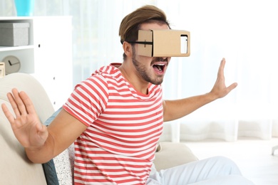 Young man using cardboard virtual reality headset at home