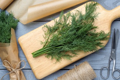 Photo of Fresh dill and scissors on grey wooden table, flat lay