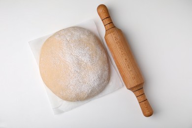 Photo of Fresh dough and rolling pin on white table, top view