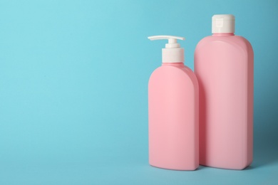 Photo of Bottles with hair care cosmetics on light blue background