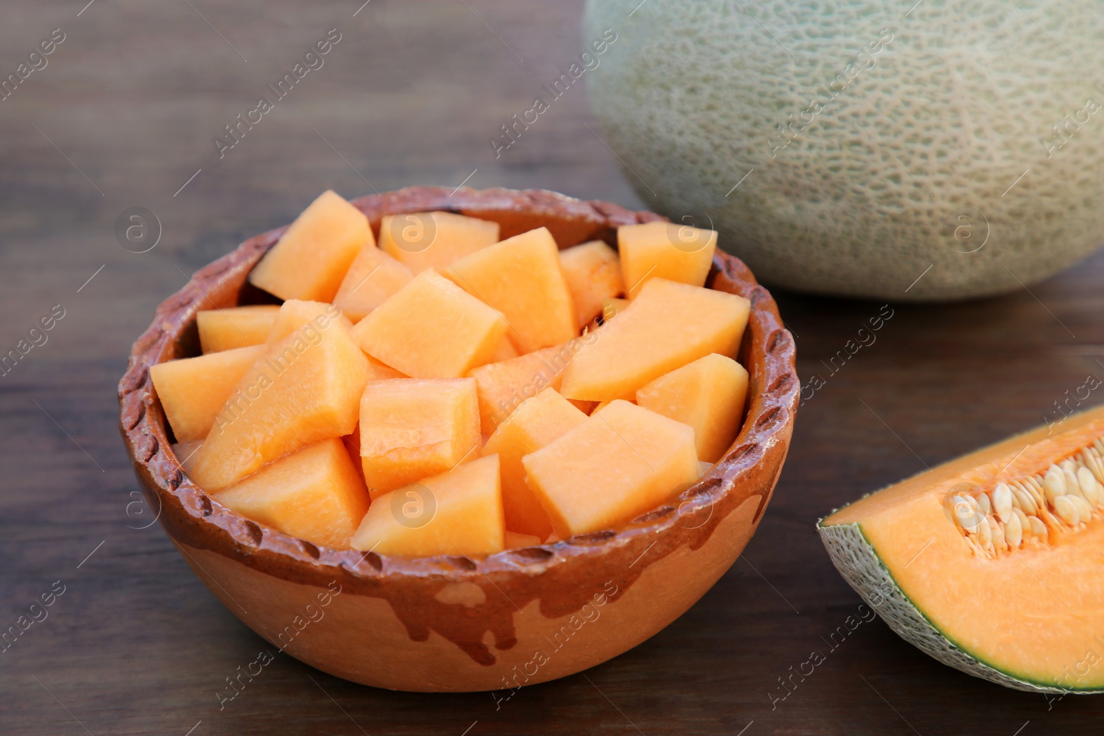 Photo of Whole and cut delicious ripe melons on wooden table, closeup