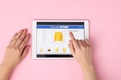 Photo of Woman with tablet shopping online on pink background, top view