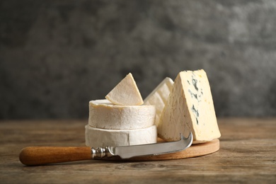 Photo of Different types of cheese and knife on wooden table