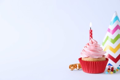 Photo of Delicious birthday cupcake with burning candle, sprinkles and party decor on white background, space for text