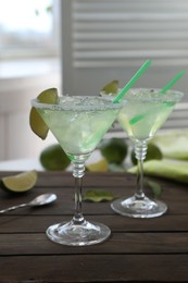 Delicious Margarita cocktail in glasses on wooden table