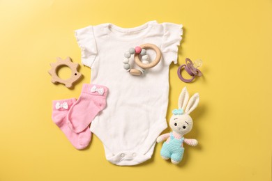 Different baby accessories on yellow background, flat lay