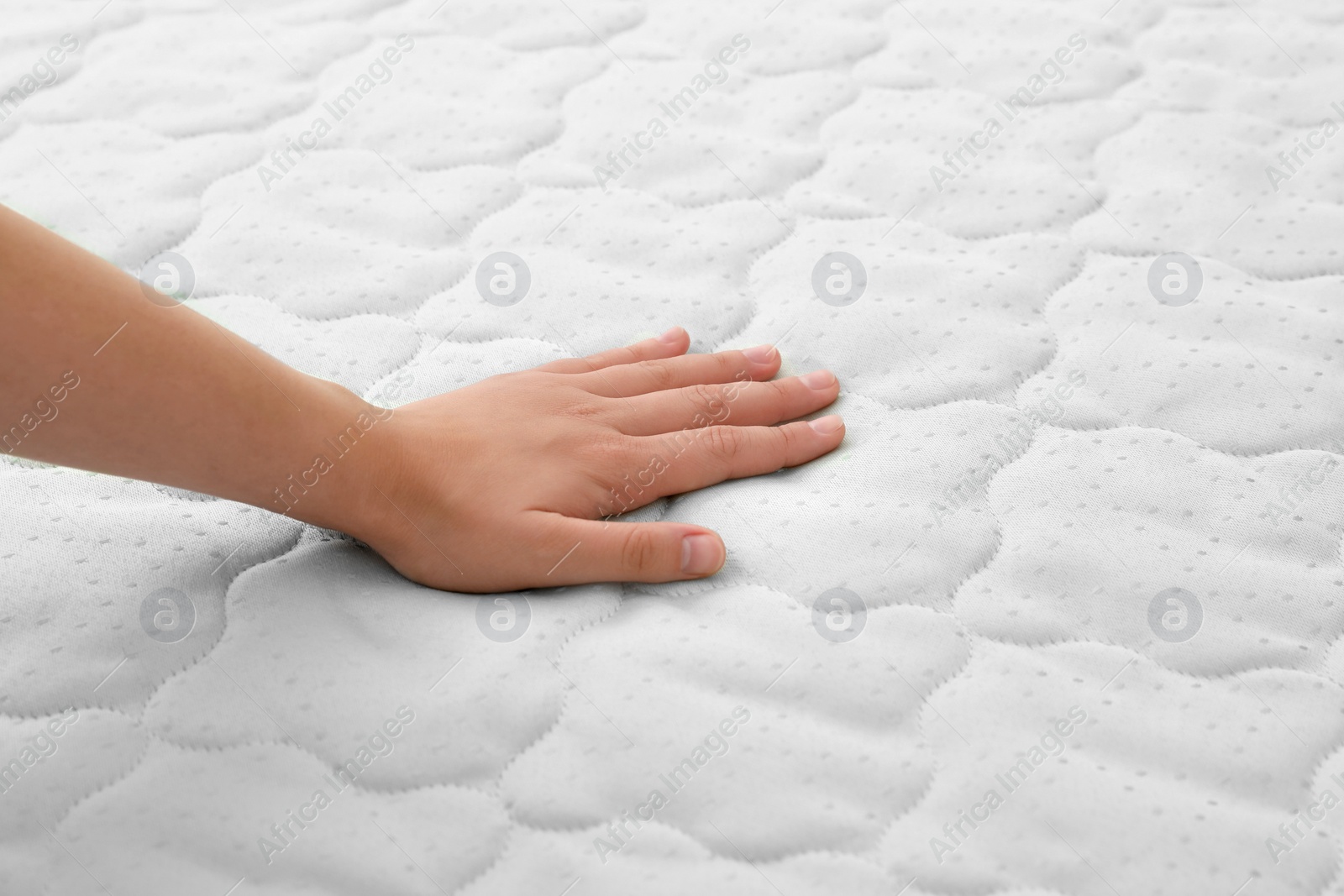 Photo of Woman touching soft light green mattress, closeup