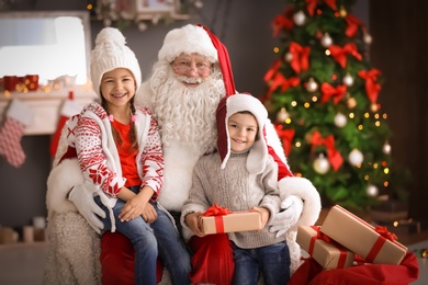 Photo of Little children and authentic Santa Claus indoors