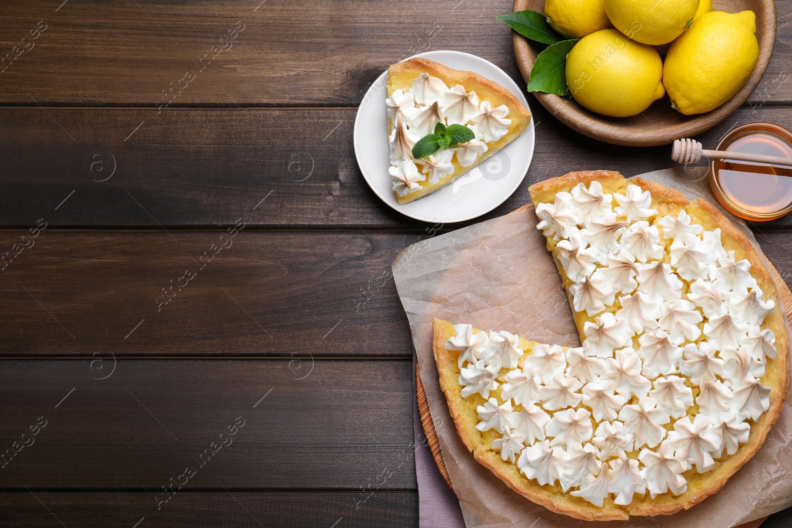 Photo of Cut delicious lemon meringue pie served on wooden table, flat lay. Space for text