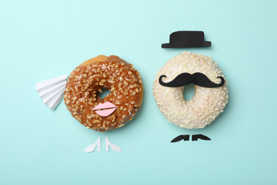 Bride and groom made with donuts on light blue background, flat lay