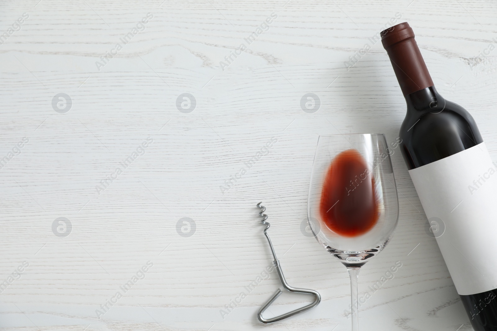 Photo of Flat lay composition with bottle of wine and elegant glass on white wooden background. Space for text