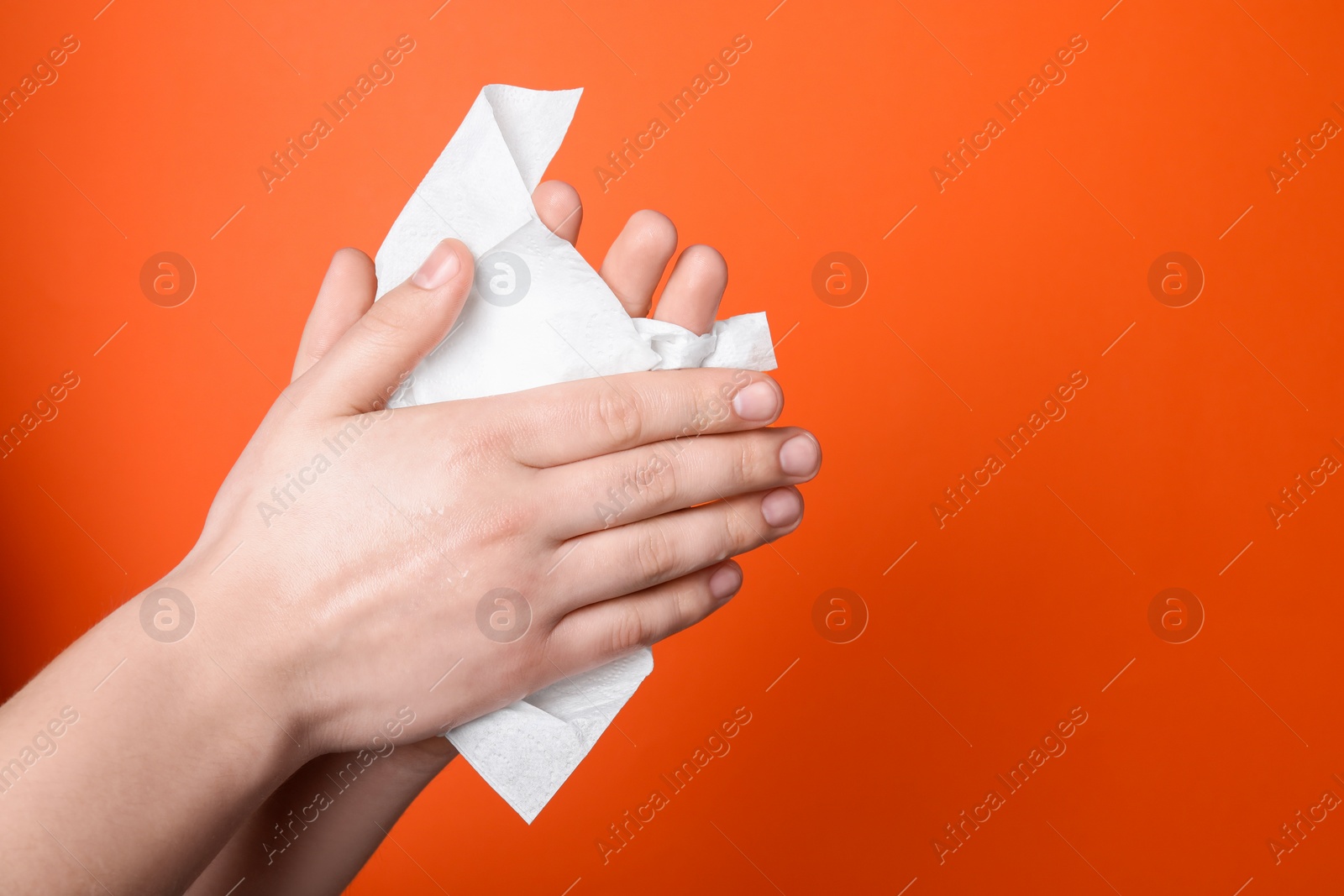 Photo of Woman wiping hands with paper towel on orange background, closeup. Space for text