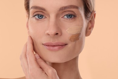 Woman with swatches of foundation on face against beige background, closeup