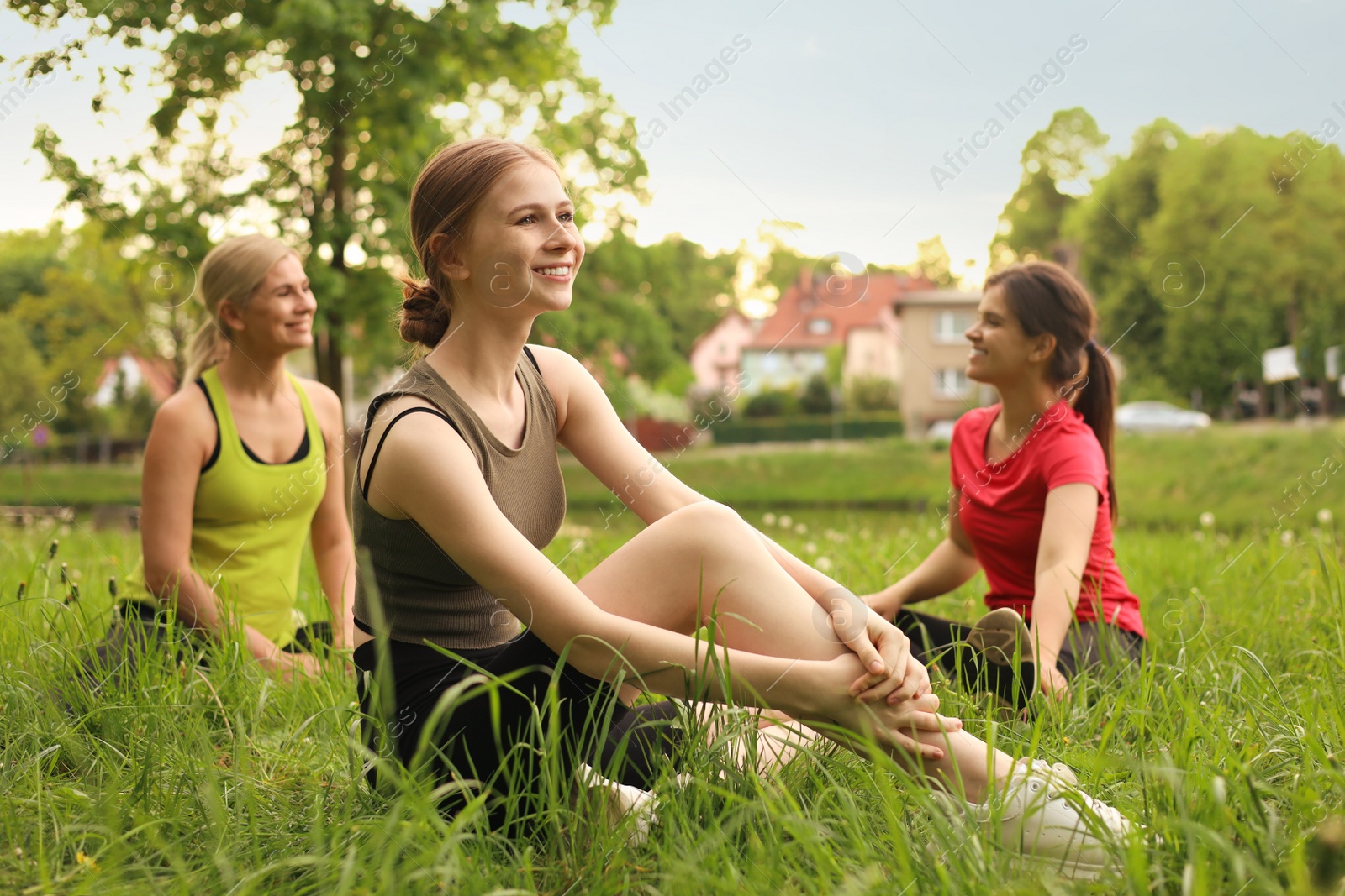 Photo of Women and teenage girl doing morning exercise on green grass in park