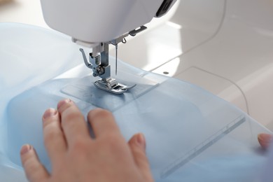 Photo of Dressmaker sewing new dress with machine in atelier, closeup