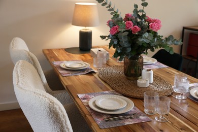 Photo of Beautiful table setting with bouquet and candles indoors. Roses and eucalyptus branches in vase