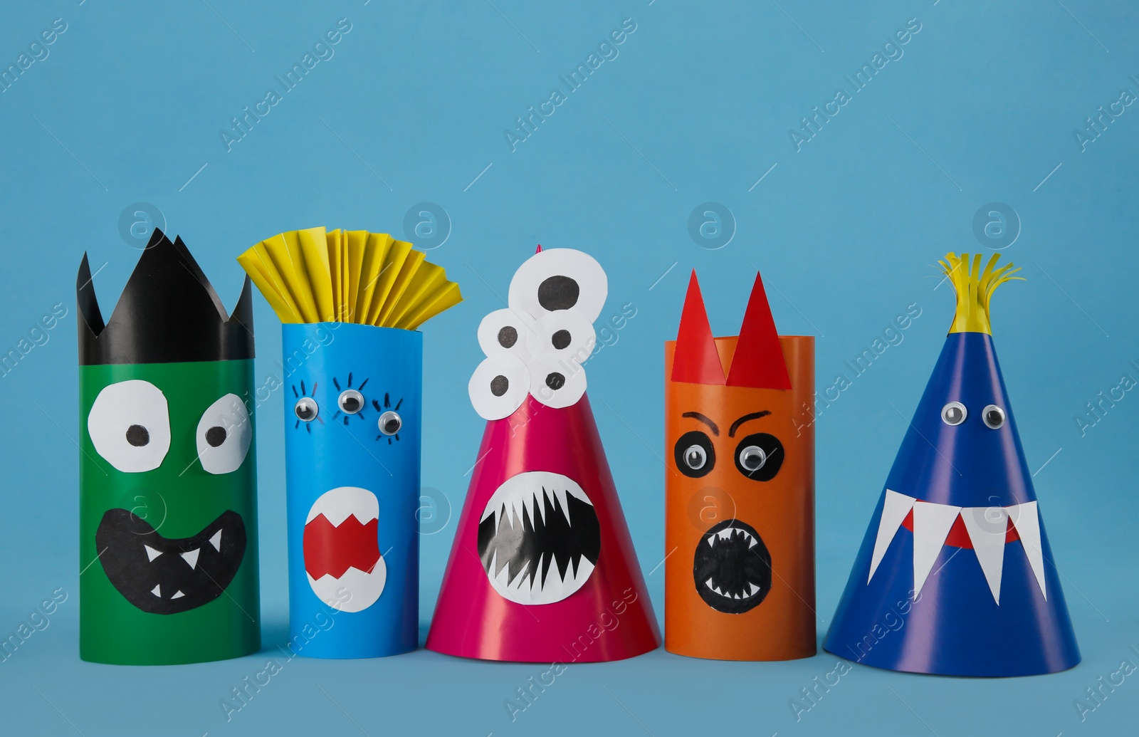 Photo of Funny monsters on light blue background. Halloween decoration