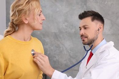Doctor listening to patient's lungs with stethoscope in clinic