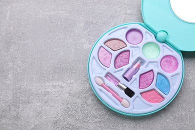 Decorative cosmetics for kids. Eye shadow palette on grey table, top view. Space for text