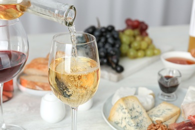 Photo of Pouring white wine into glass on served table. Space for text