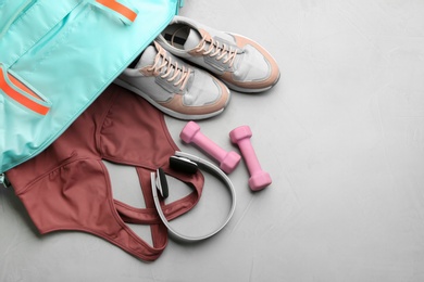 Flat lay composition with gym bag and sportswear on grey table. Space for text