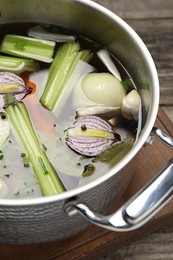 Photo of Different ingredients for cooking tasty bouillon in pot on wooden table, closeup