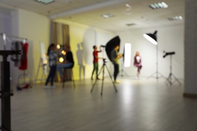 Photo of Blurred photo studio with professional equipment and team of workers