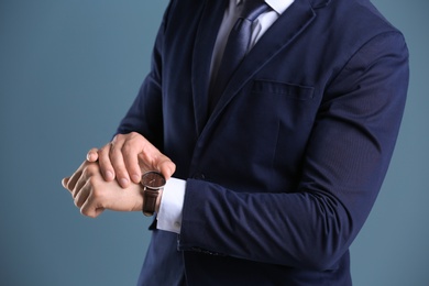 Businessman with wristwatch on color background. Time concept