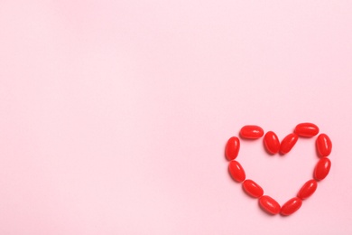 Photo of Heart of jelly beans on color background, top view. Space for text