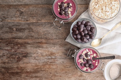 Photo of Flat lay composition with jars of tasty acai smoothie on wooden table