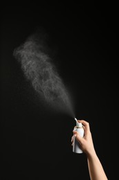 Photo of Nasal congestion. Woman spraying remedy from bottle on black background, closeup