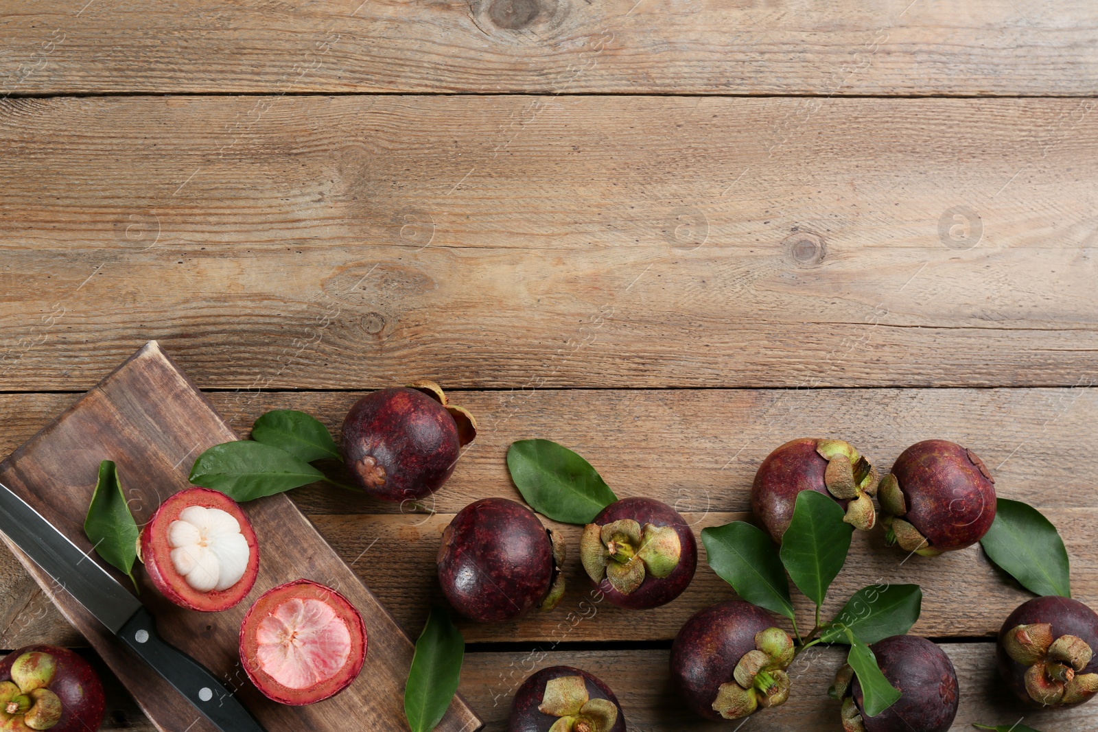 Photo of Delicious tropical mangosteens on wooden table, flat lay. Space for text