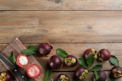 Delicious tropical mangosteens on wooden table, flat lay. Space for text