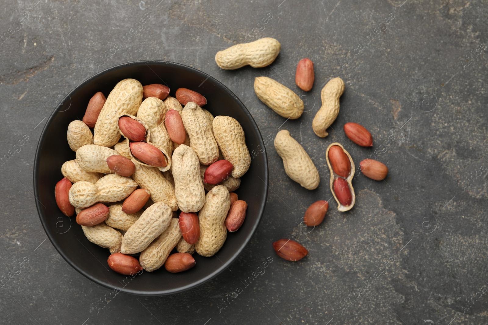 Photo of Fresh unpeeled peanuts in bowl on grey table, top view