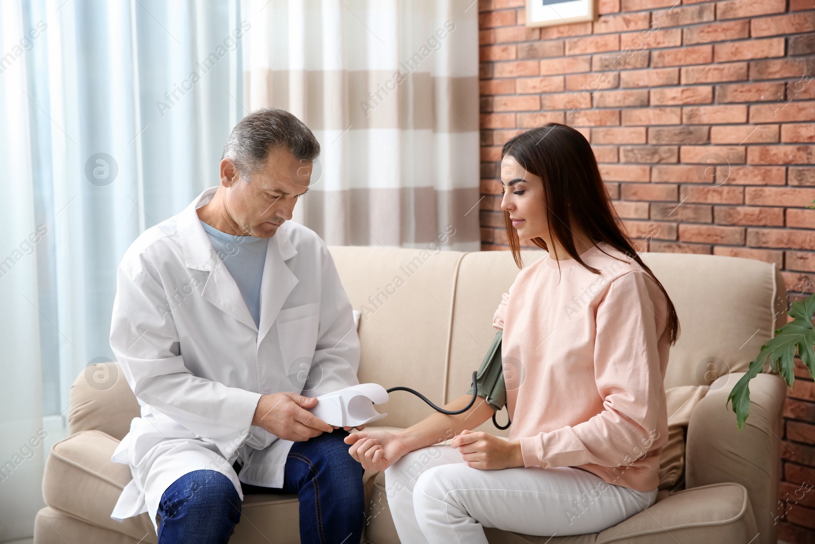 Photo of Doctor checking young woman's pulse with medical device at home