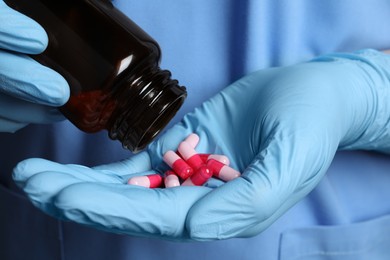 Doctor pouring pills from bottle onto hand, closeup view