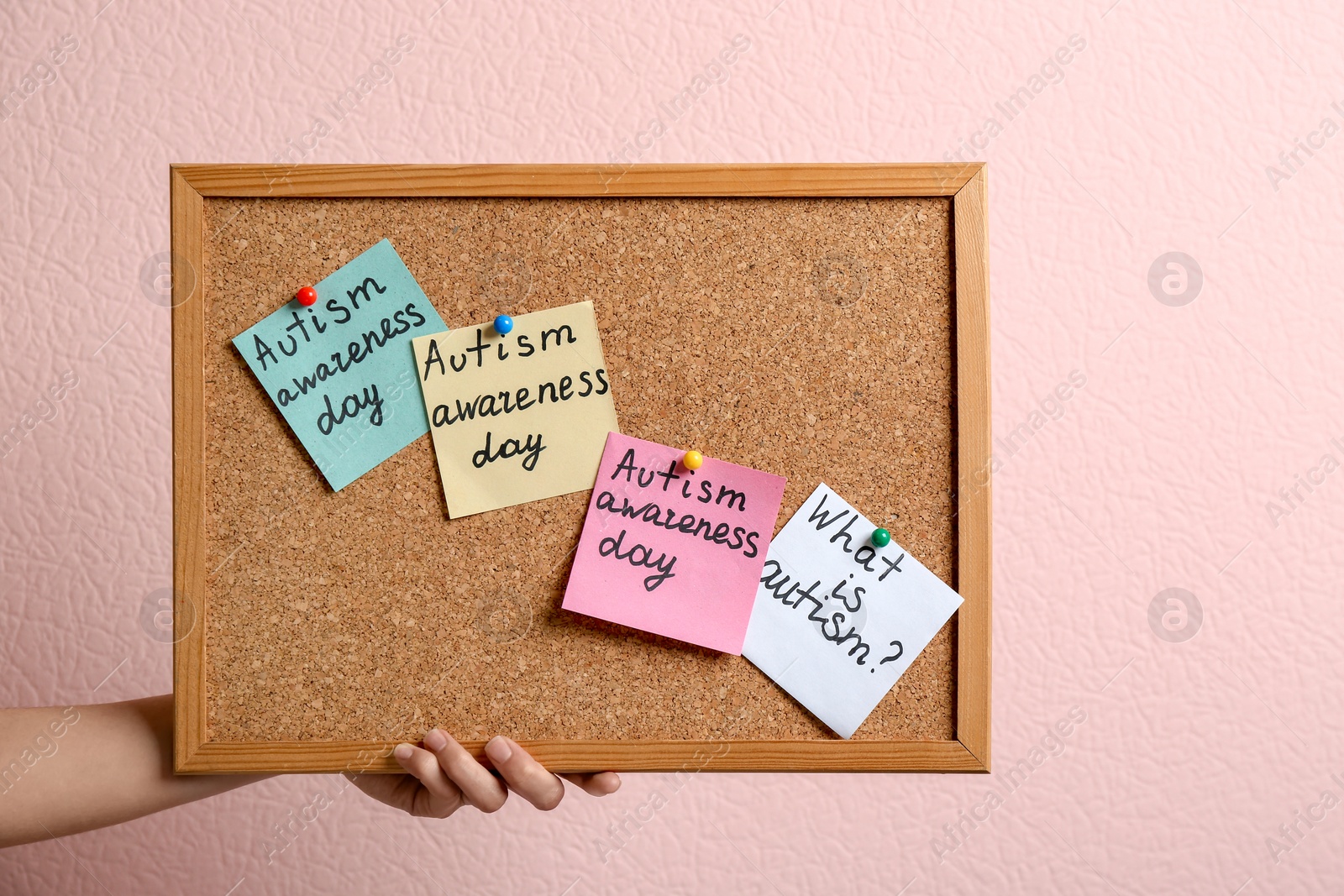 Photo of Woman holding board with autism related phrases on color background