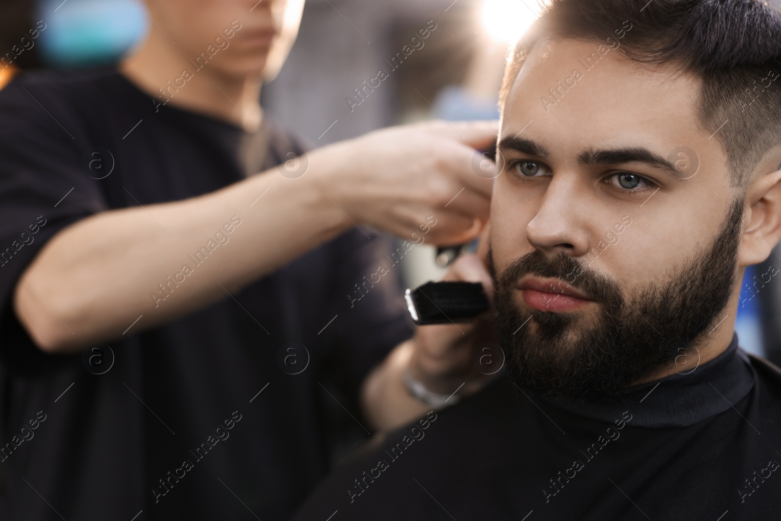 Photo of Professional hairdresser working with client in barbershop