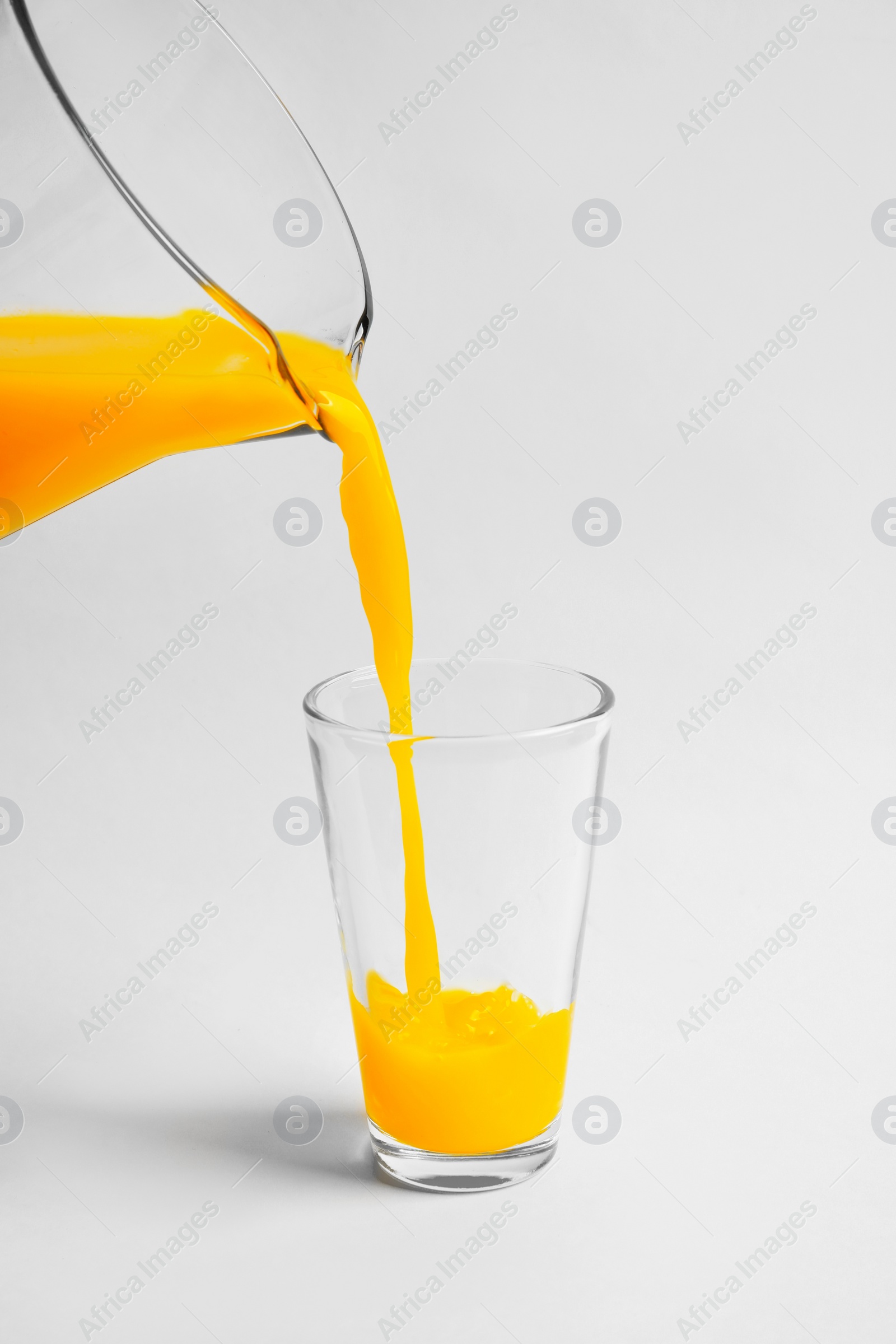 Photo of Pouring fresh orange juice into glass on white background