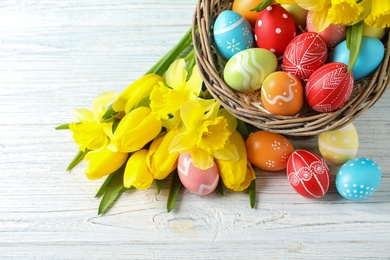 Composition with colorful painted Easter eggs and flowers on wooden background, top view