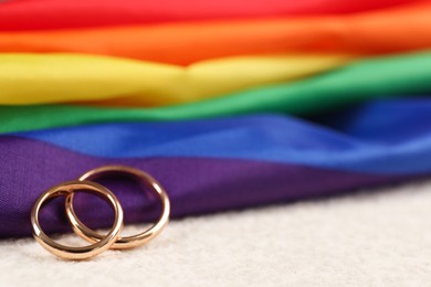 Rainbow LGBT flag and wedding rings on white background, closeup