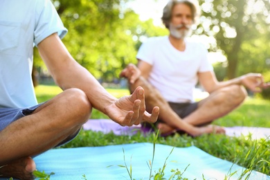 Photo of Men practicing morning yoga in sunny park, closeup